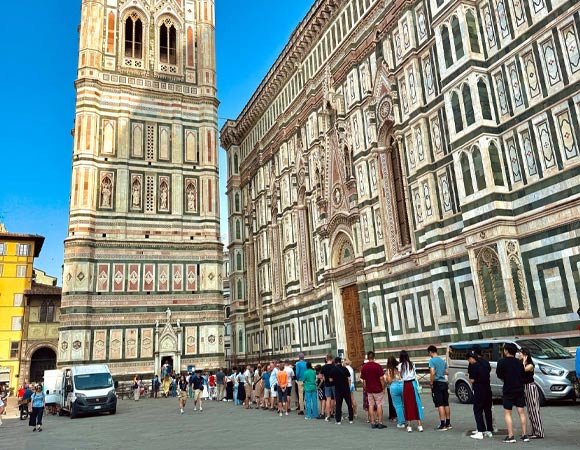 Long line of visitors waiting outside Florence Cathedral, with a clear view of Giotto’s Bell Tower and the cathedral’s intricate marble façade.